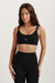 Woman wearing a black sports bra and leggings with 'SET' branding on a light background <model-info>Brinley wears a size XS and is 5’8, 23” waist, 32A bust.</model-info> 