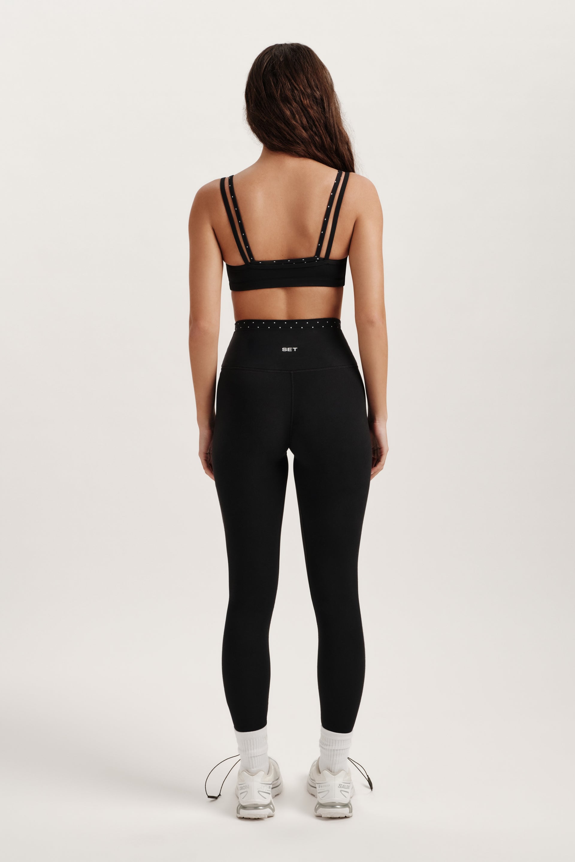 Person wearing a black sports bra and leggings on a white background