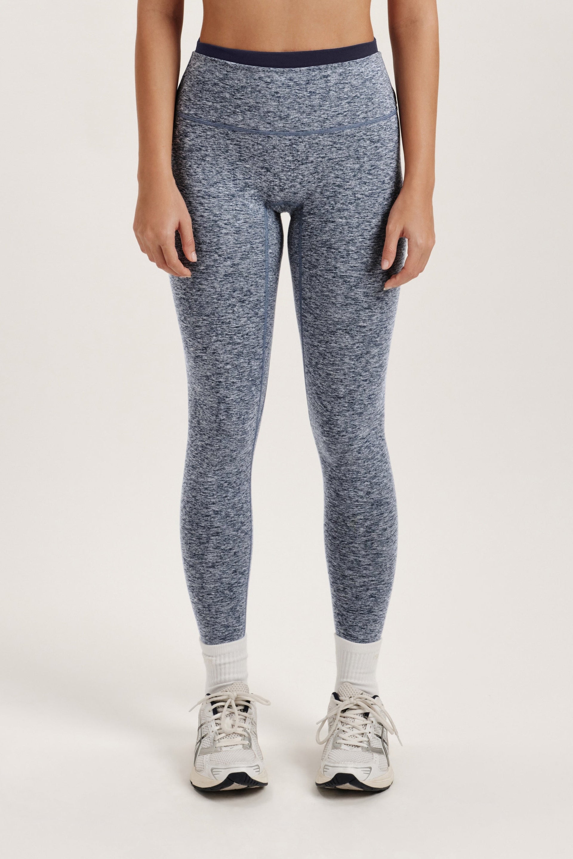 Woman wearing a gray athletic bra and leggings set on a white background <model-info>Brinley wears a size XS and is 5’8, 23” waist, 32A bust.</model-info> 