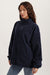 Woman wearing a navy fleece jacket on a plain background <model-info>Brinley wears a size S and is 5’8, 23” waist, 32A bust.</model-info> 