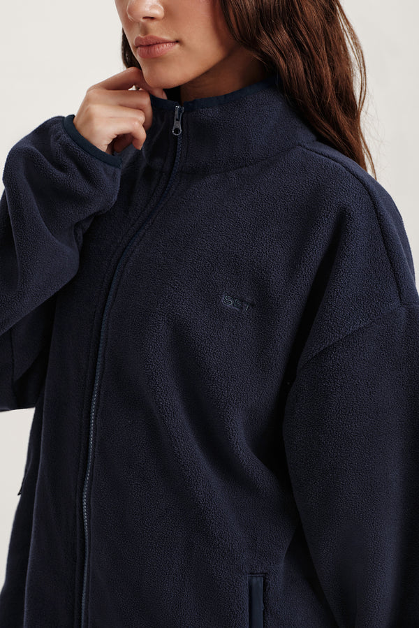 Person wearing a navy blue jacket with a brand logo on a white background