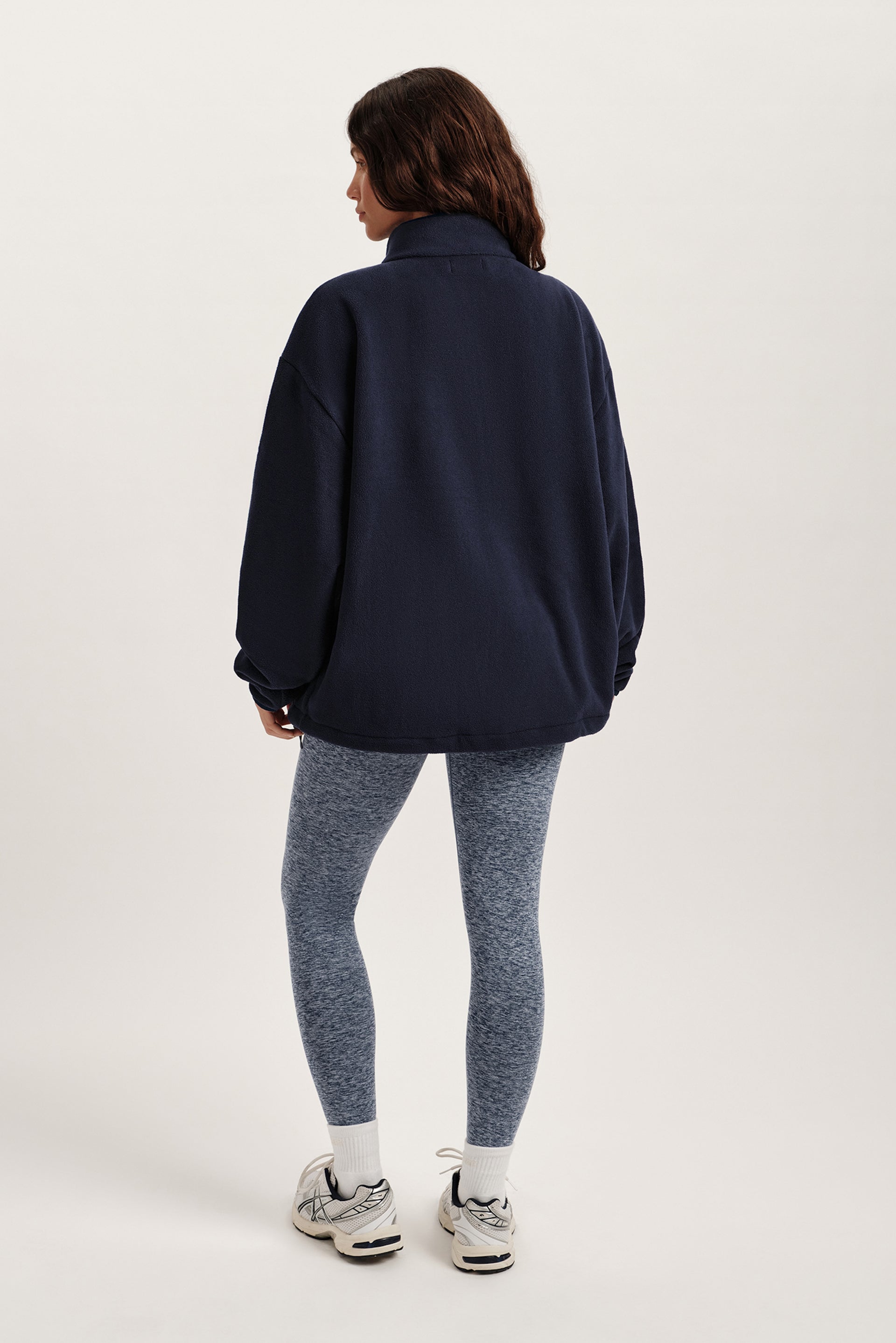 Person wearing a navy jacket and gray leggings on a white background