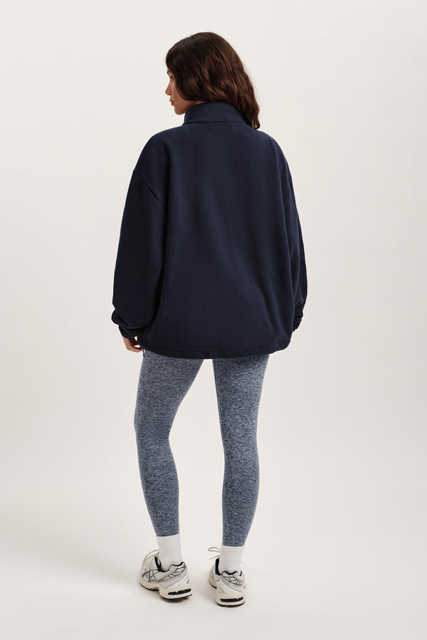 Person wearing a navy jacket and gray leggings on a white background