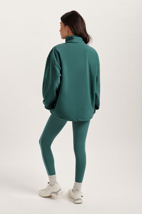 Person wearing a teal tracksuit on a white background