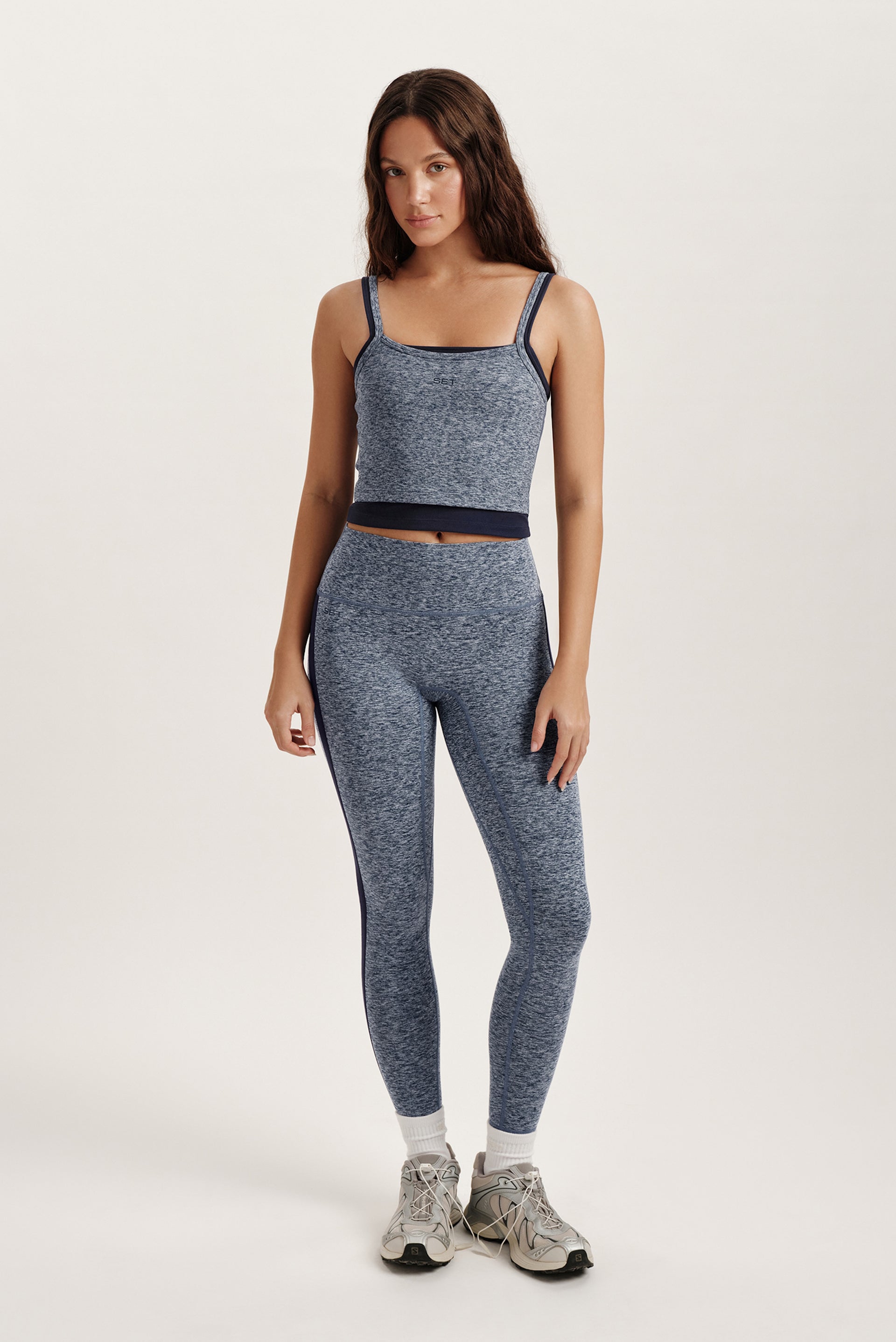 Woman wearing a gray athletic outfit on a white background