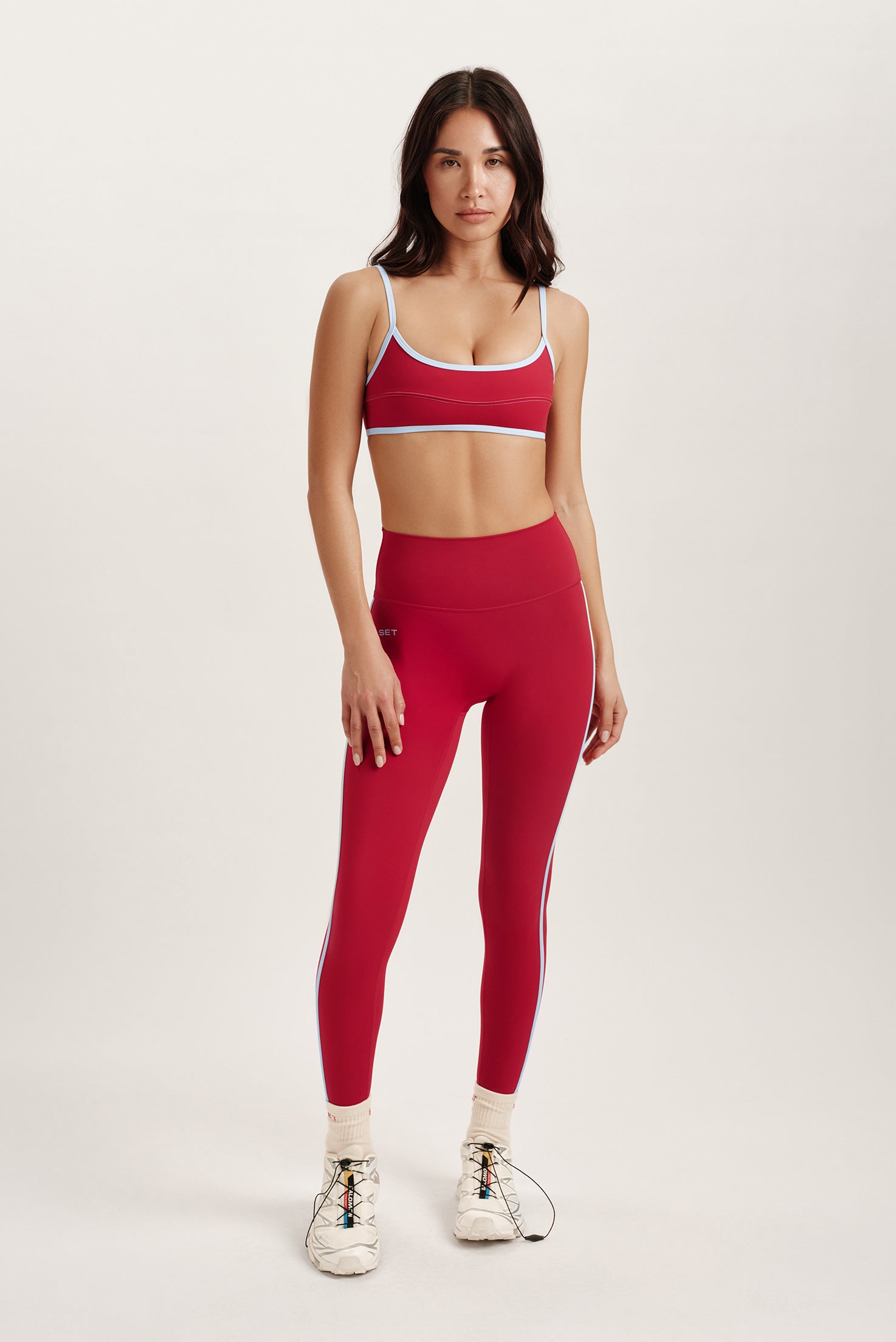 Woman wearing a red sports bra and leggings set on a white background