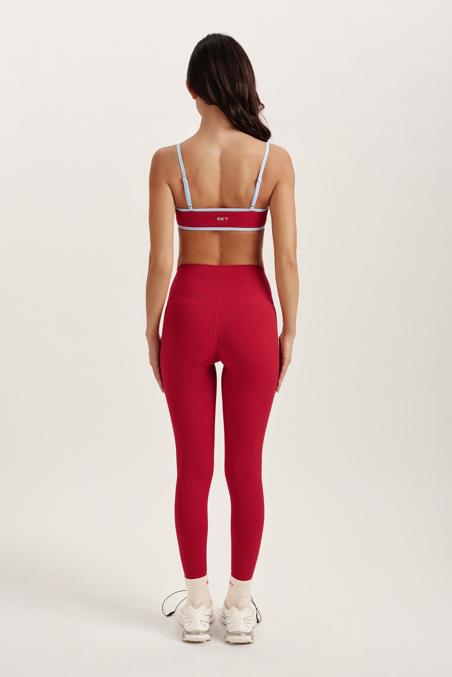 Woman wearing a red sports bra and leggings set on a white background