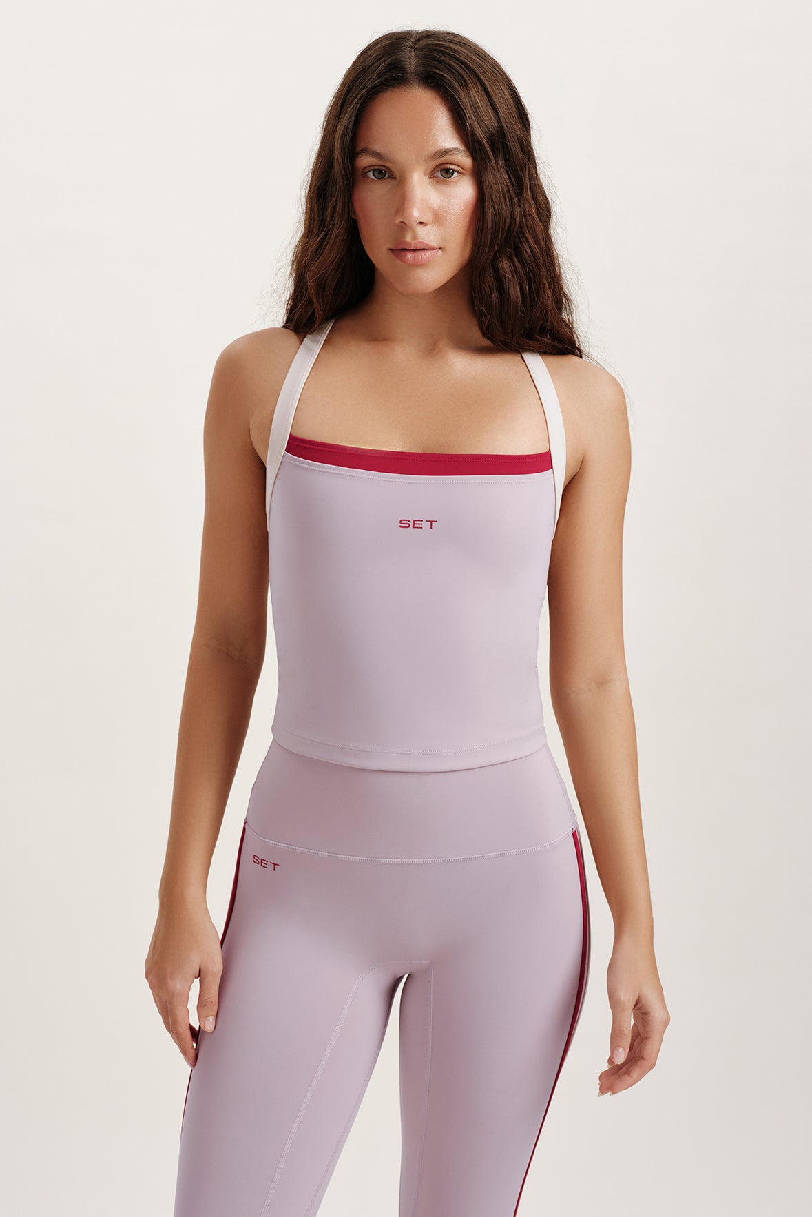Woman wearing a light purple athletic outfit with a red accent on a white background <model-info>Brinley wears a size XS and is 5’8, 23” waist, 32A bust.</model-info> 