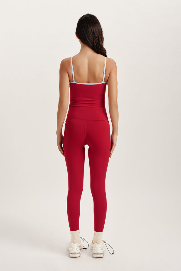 Person wearing a red athletic set with thin straps on a white background