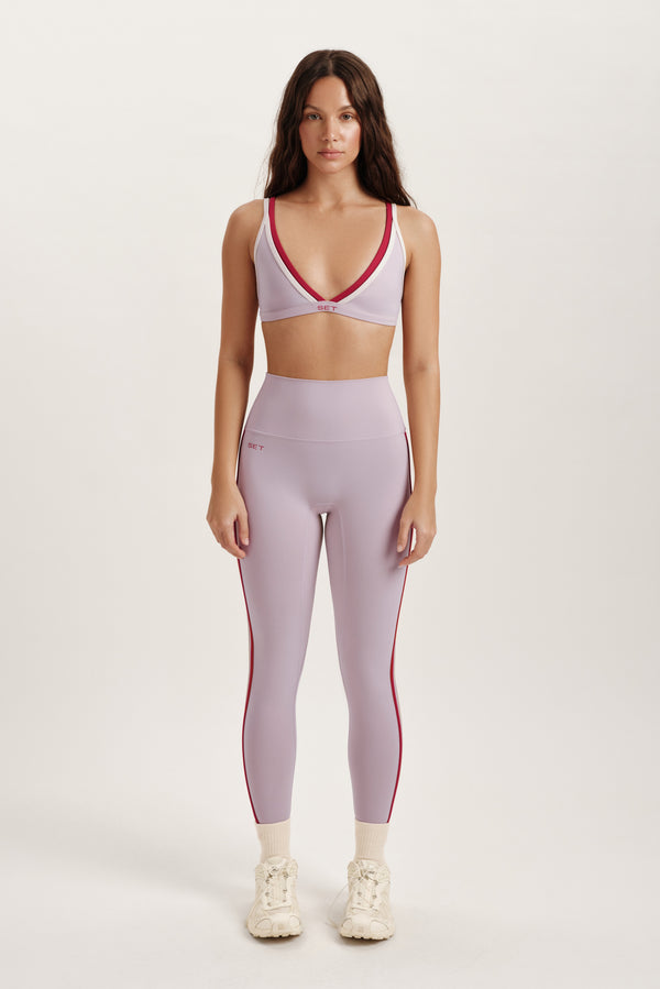 Woman wearing a sports bra and leggings set on a white background