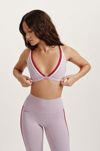 Woman wearing a sports bra and leggings with red accents on a white background 