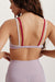 Person wearing a light purple sports bra and leggings with red straps on a neutral background