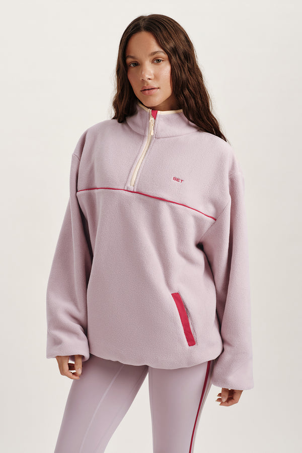 Woman wearing a light purple pullover with red accents on a white background