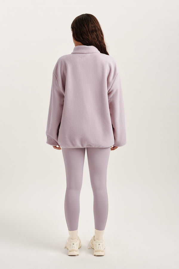 Person wearing a light purple outfit on a white background