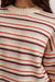Close-up of a person wearing a striped sweater with red, brown, and beige colors.