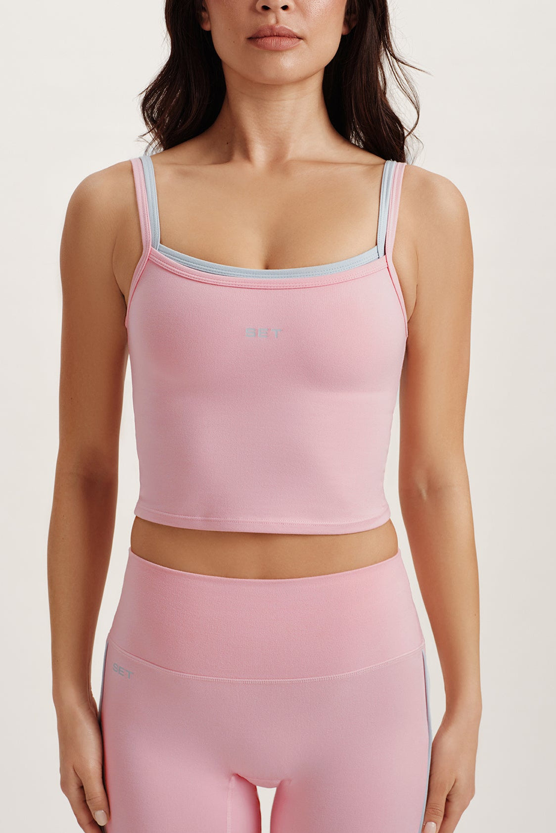Woman wearing a pink athletic outfit with a white background