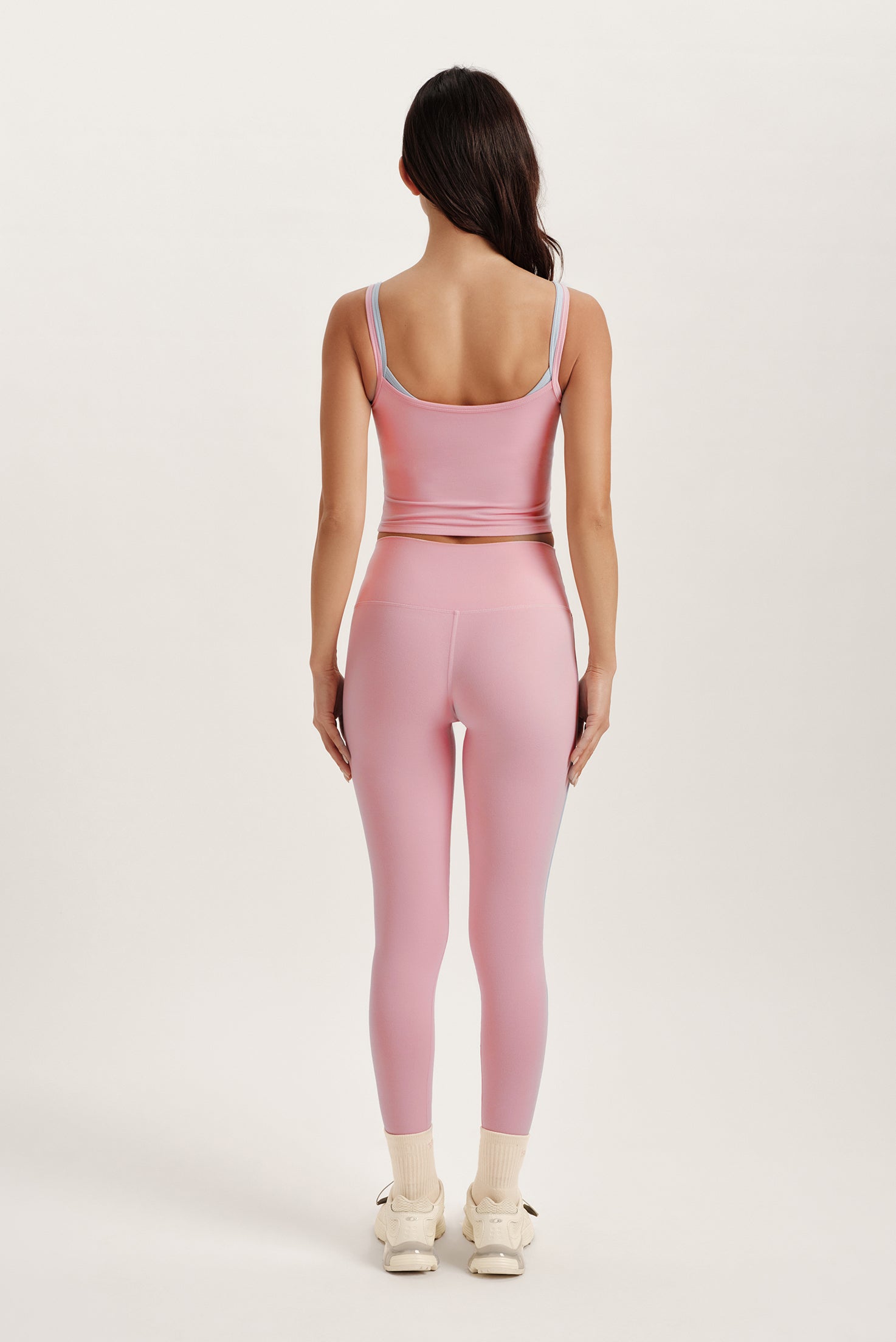 Person wearing a pink tank top and leggings set on a white background