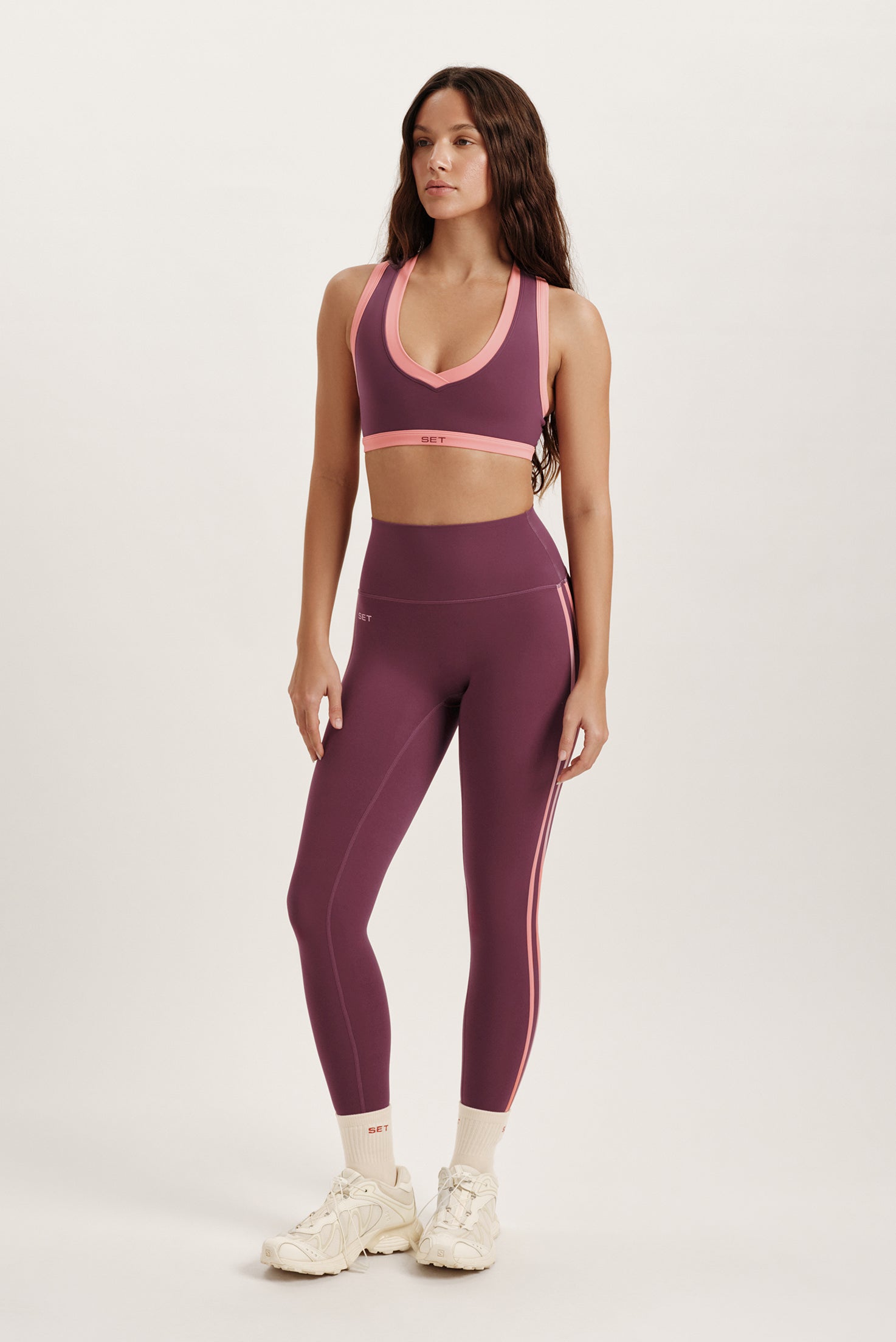 Woman wearing a purple sports bra and leggings set on a white background