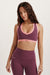 Woman wearing a purple sports bra and leggings with pink accents on a white background <model-info>Brinley wears a size XS and is 5’8, 23” waist, 32A bust.</model-info> 