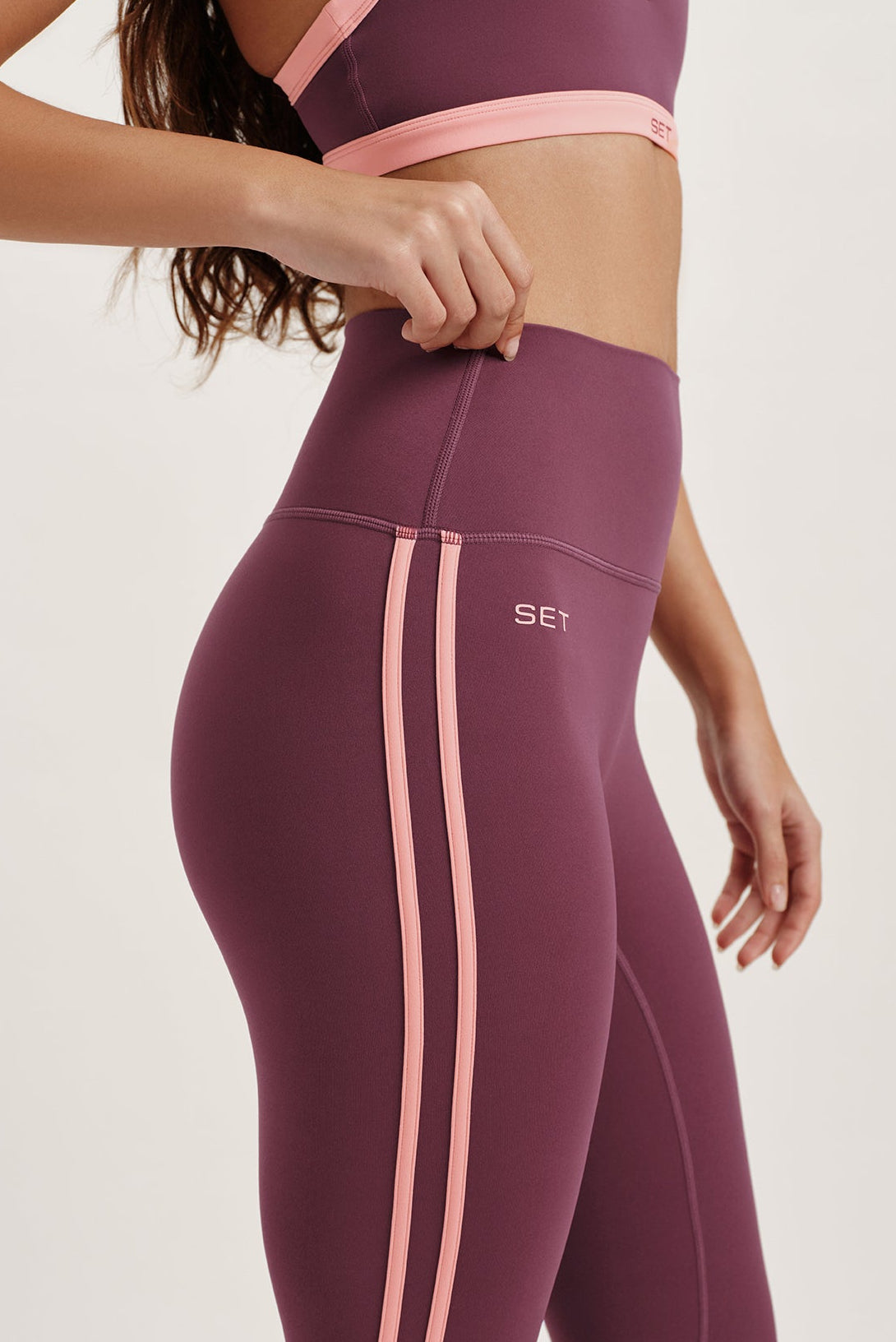 Maroon leggings with pink accents featuring the brand 'SET' on a light background