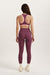 Person wearing a purple sports bra and leggings set on a white background