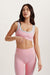 Woman wearing a pink sports bra and leggings on a light background <model-info>Jocelyn wears a size S and is 5’9, 23” waist, 32B bust.</model-info> 