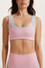 Woman wearing a pink sports bra and leggings set on a white background