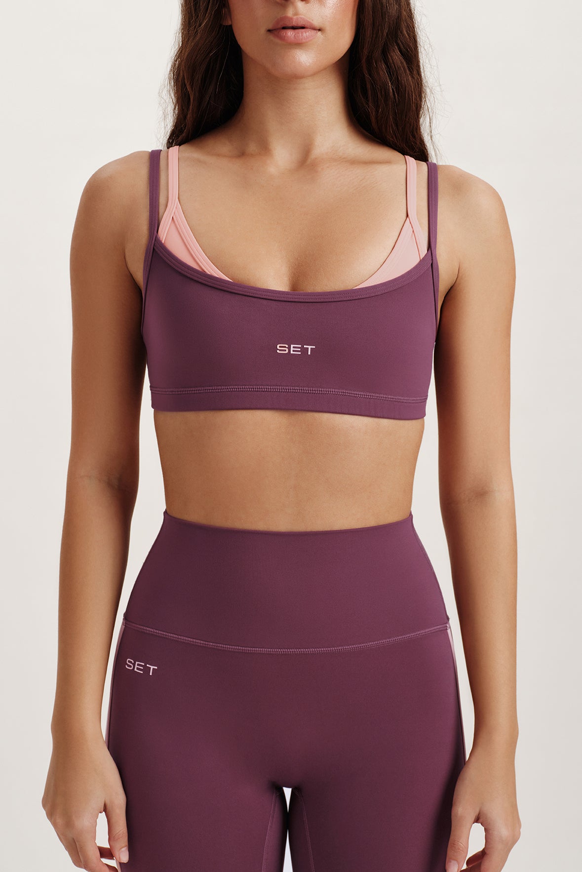 Woman wearing a purple sports bra and leggings with 'SET' branding on a white background