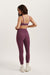 Woman wearing a purple sports bra and leggings set on a white background