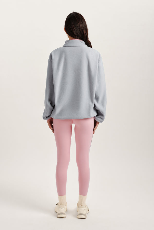 Person wearing a light blue sweater and pink leggings on a white background