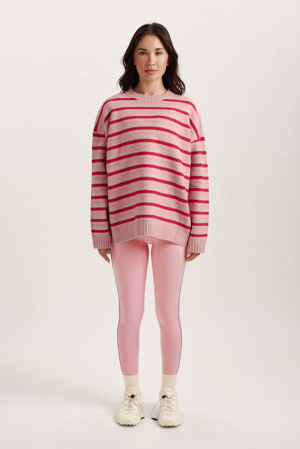 Woman wearing a pink and red striped sweater and pink leggings on a white background