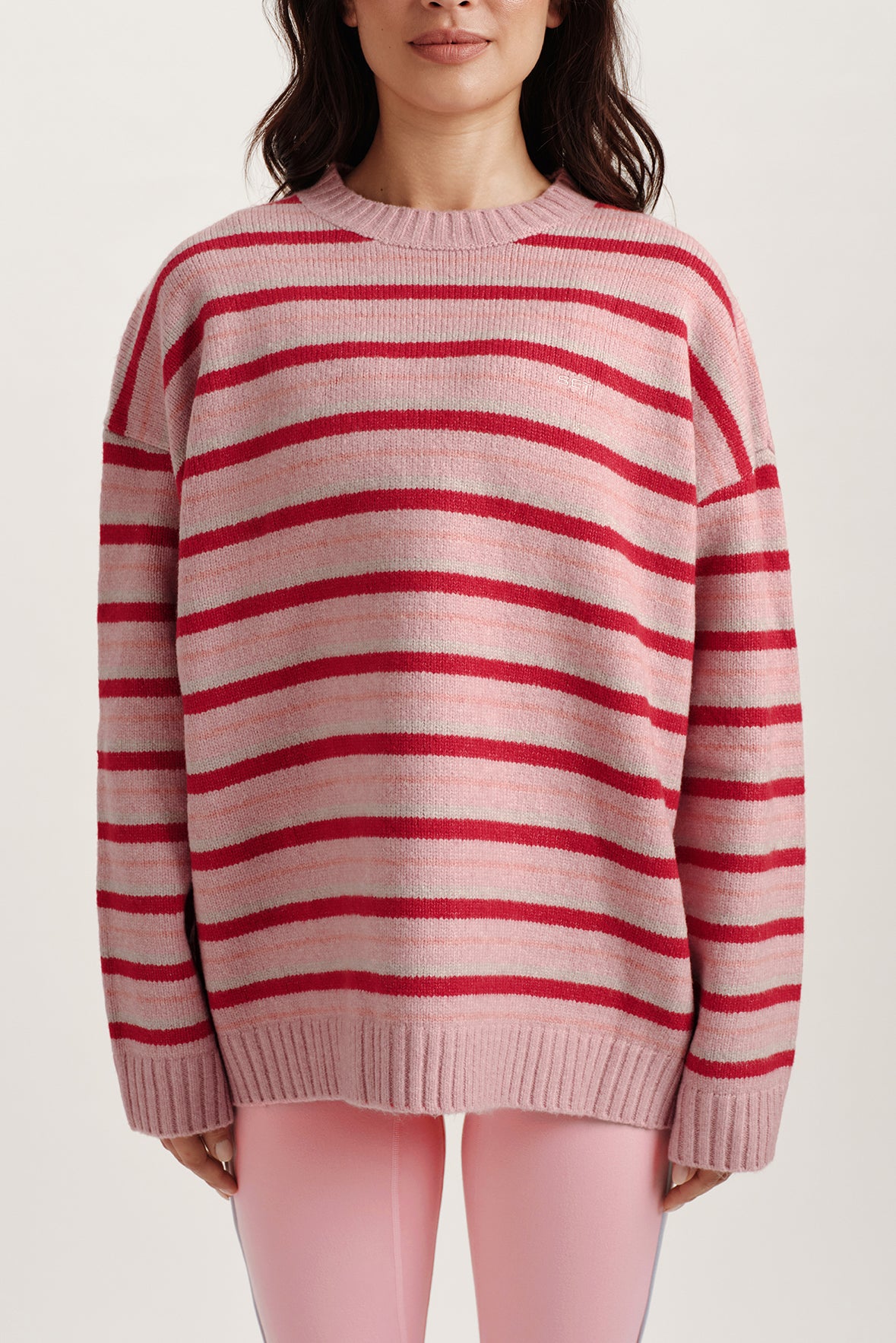 Person wearing a pink and red striped sweater on a white background