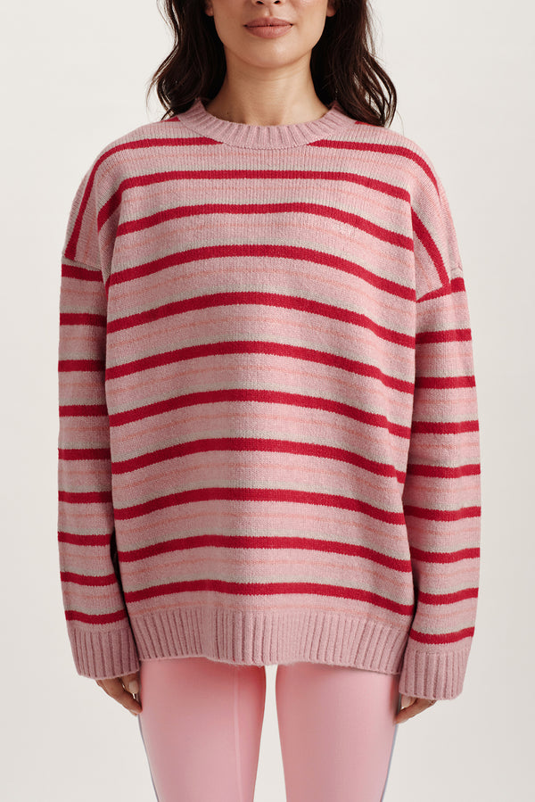Person wearing a pink and red striped sweater on a white background