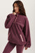Woman wearing a maroon fleece pullover with a small logo on a white background