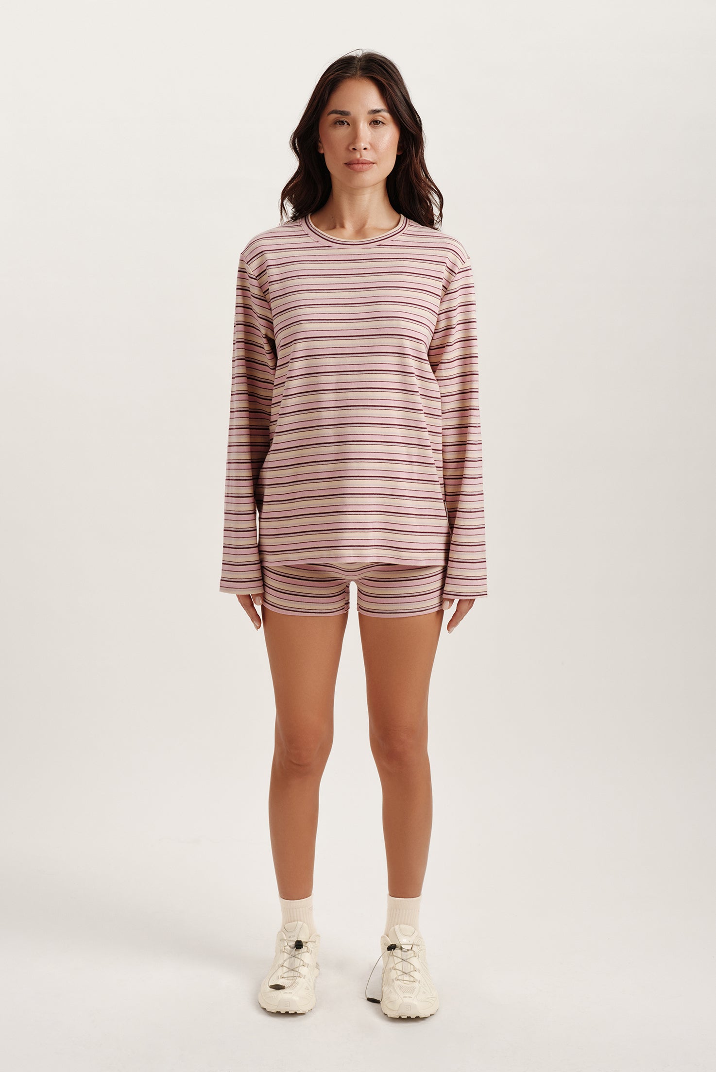 Woman wearing a striped long-sleeve shirt and shorts on a white background