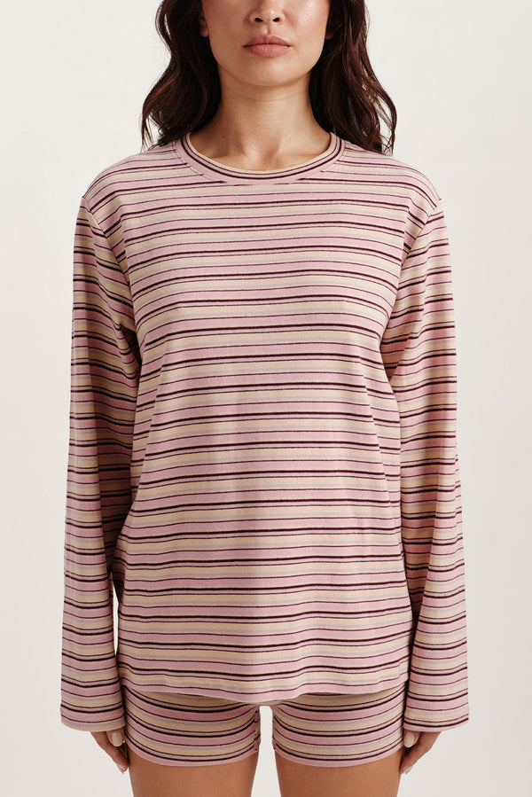 Woman wearing a striped long-sleeve top and shorts on a plain background