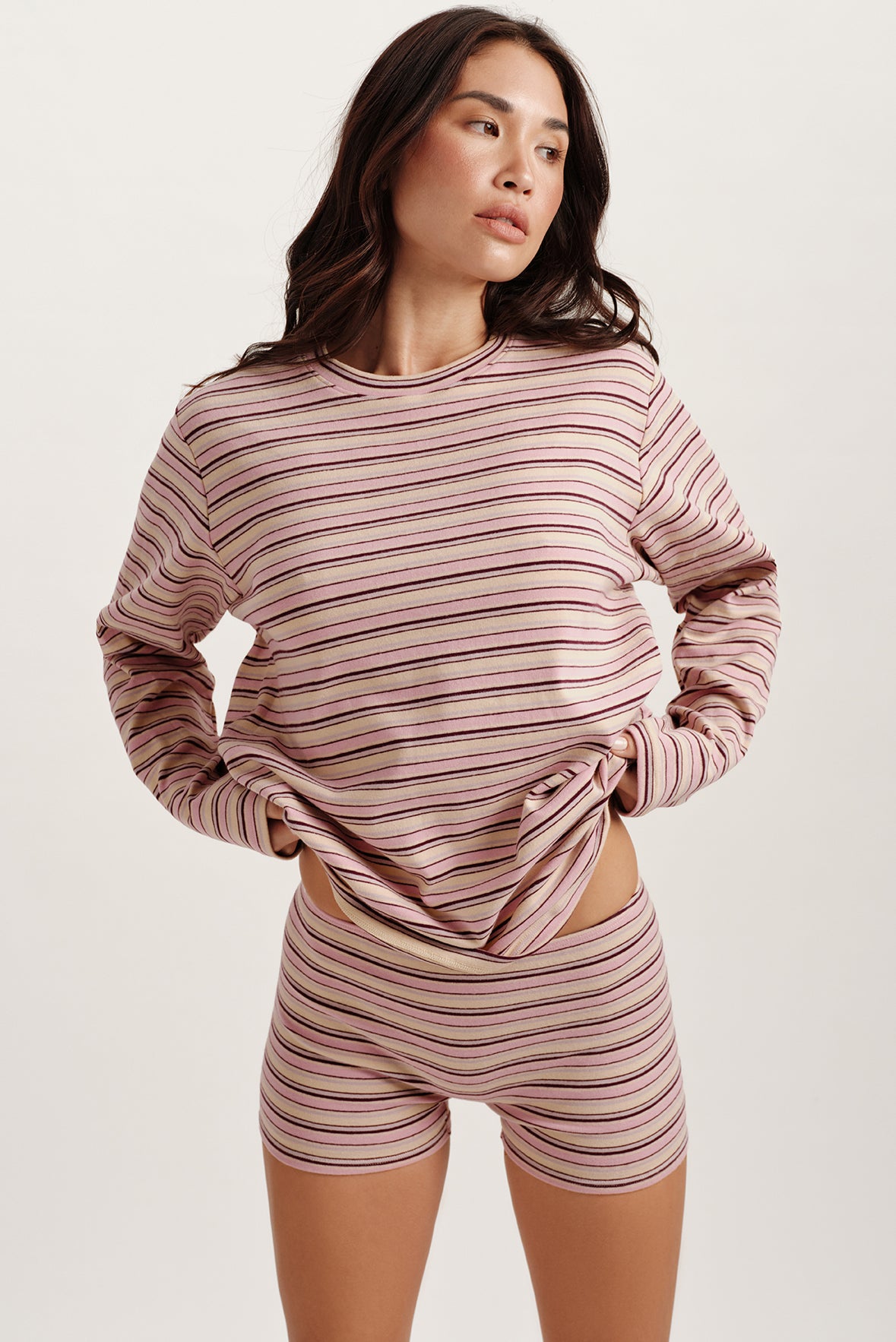 Woman wearing a matching striped long-sleeve top and shorts set on a white background