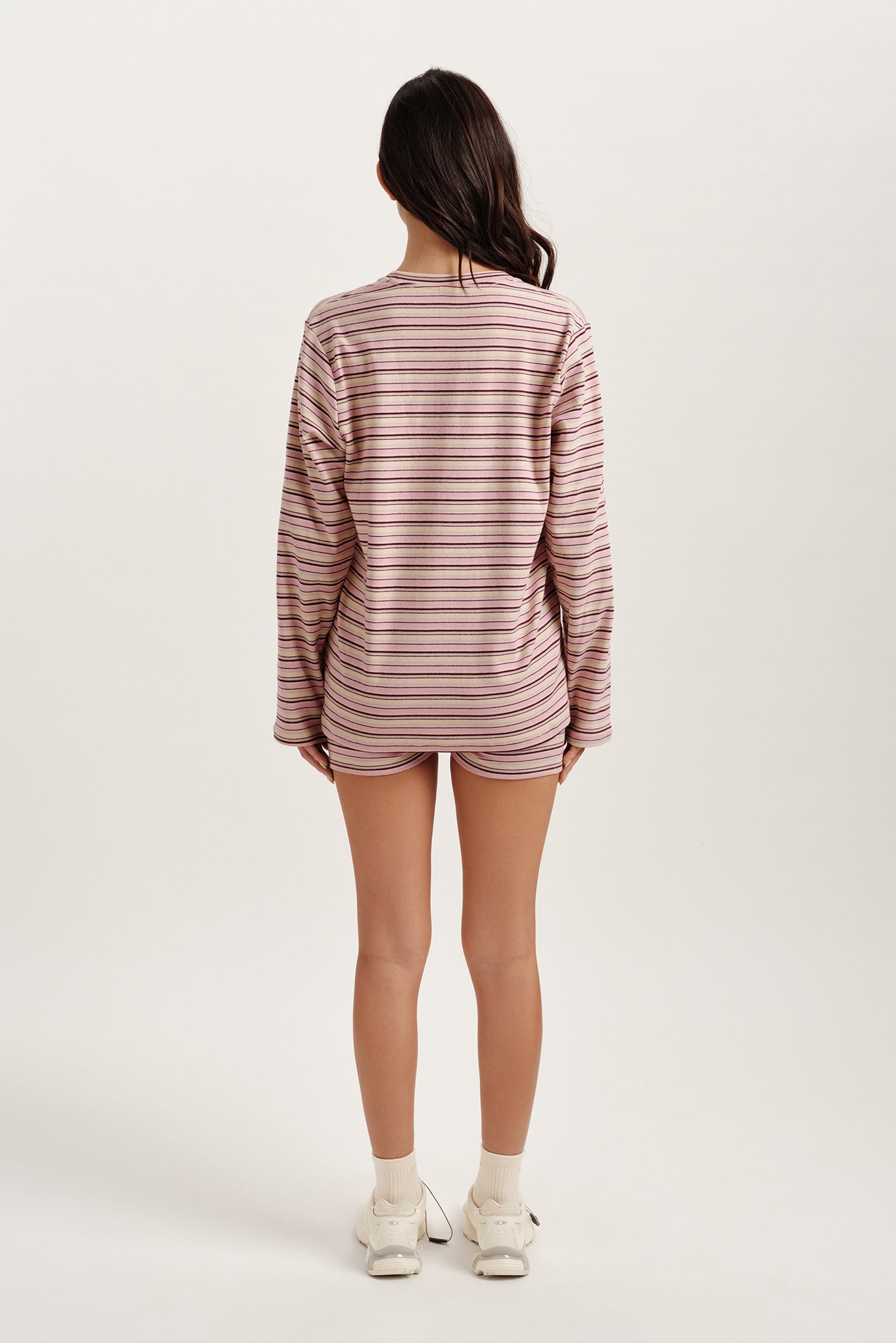 Person wearing a striped long-sleeve shirt and shorts on a white background