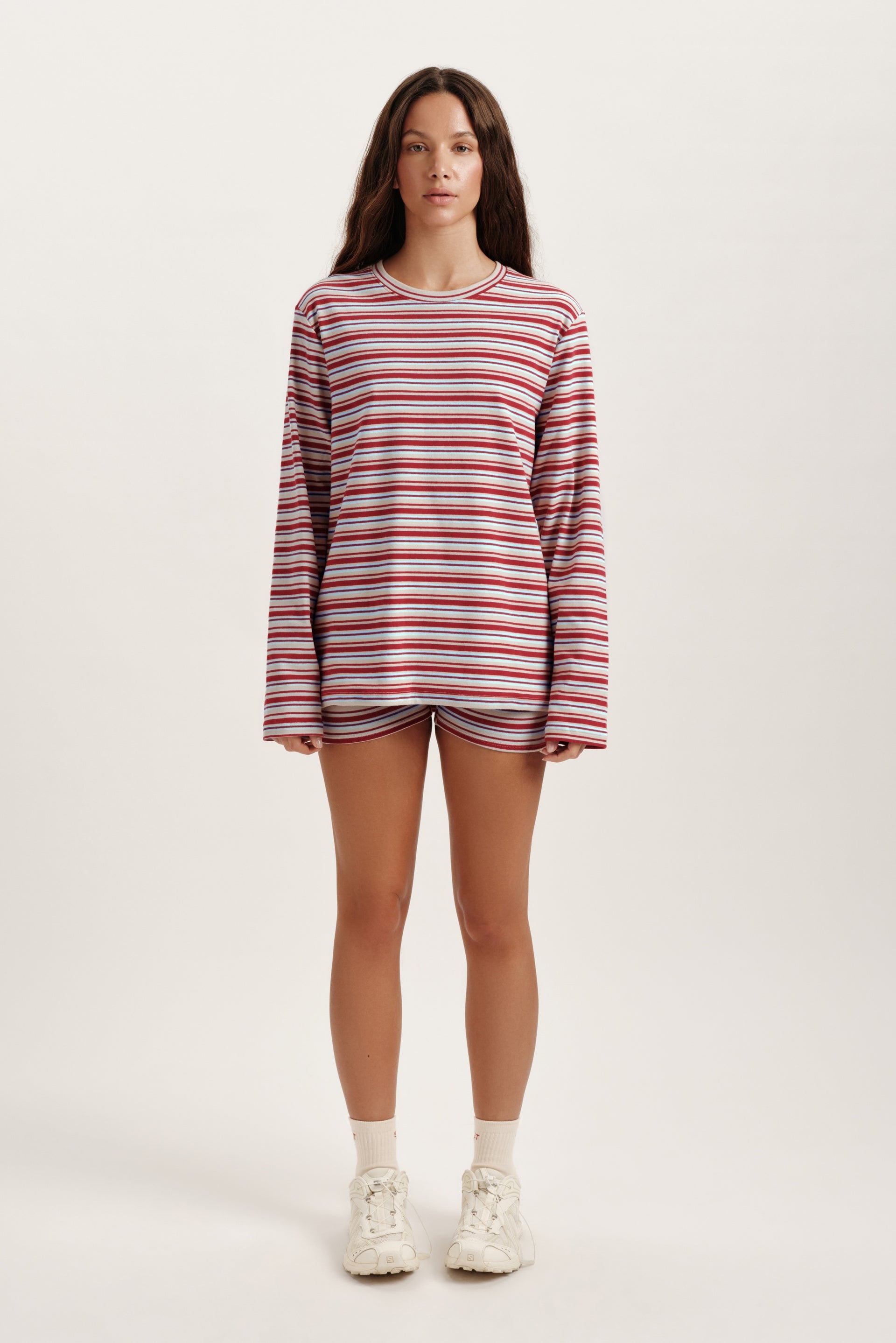 Person wearing a striped long-sleeve shirt and shorts on a white background