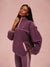 Woman wearing a purple fleece pullover against a pink background