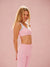 Woman wearing a pink sports bra and leggings against a pink background