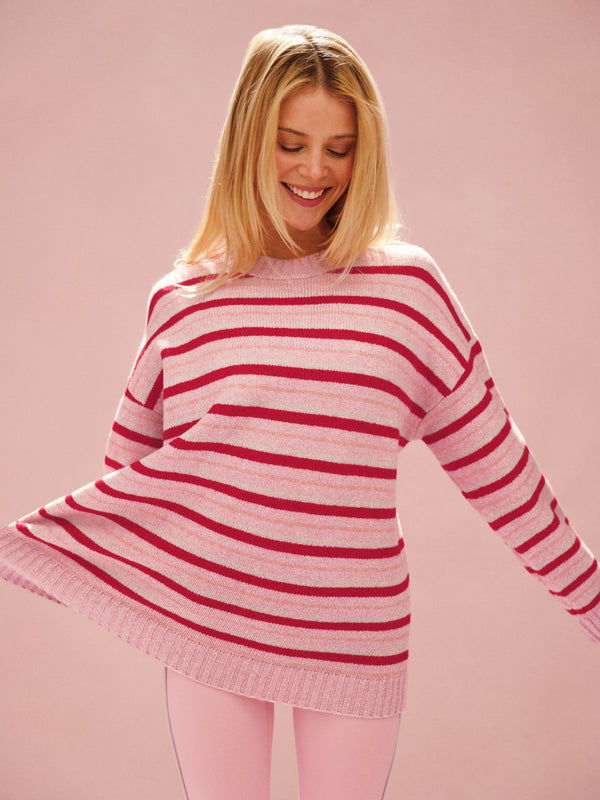 Woman wearing a pink and red striped sweater on a pink background