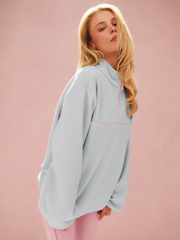 Woman wearing a light blue oversized hoodie against a pink background