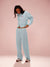Woman wearing a light blue tracksuit with 'SET' text on a pink background