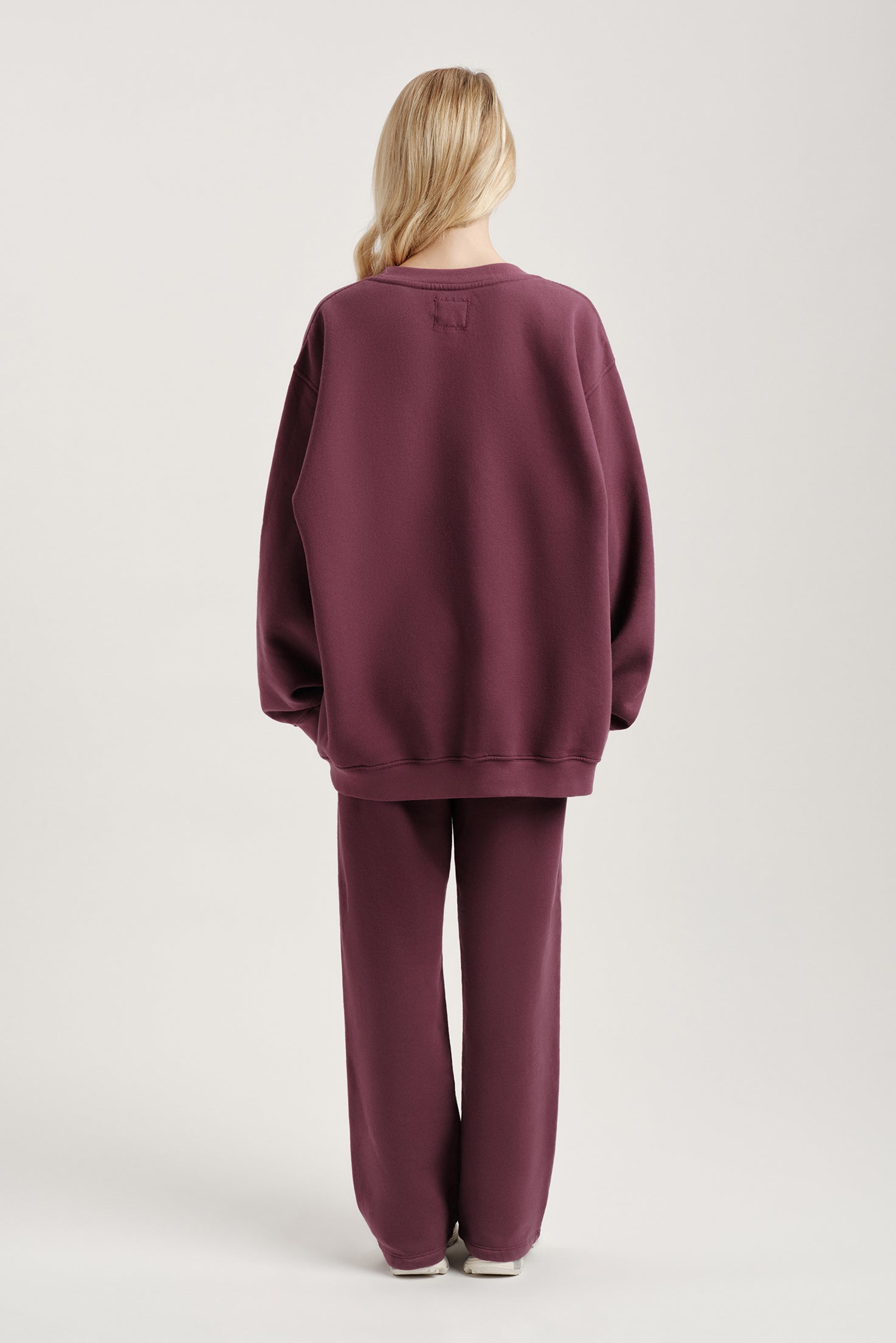 Person wearing a maroon tracksuit on a light gray background