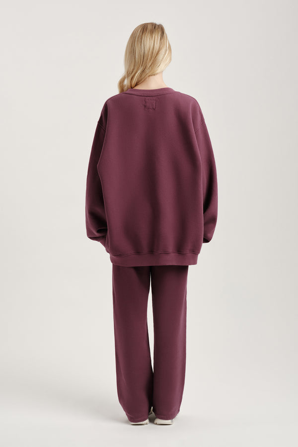 Person wearing a maroon tracksuit on a light gray background