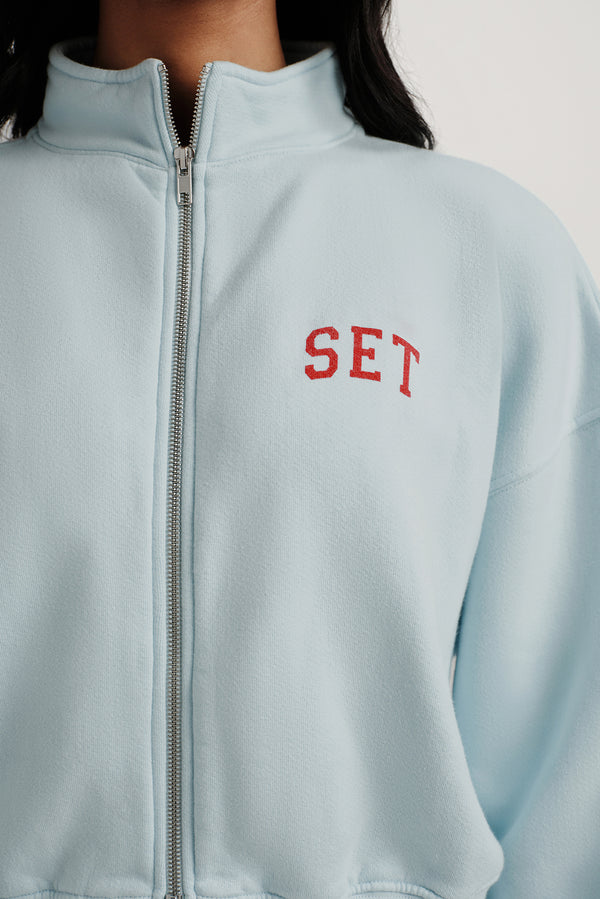 Light blue jacket with 'SET' embroidered on the chest against a white background