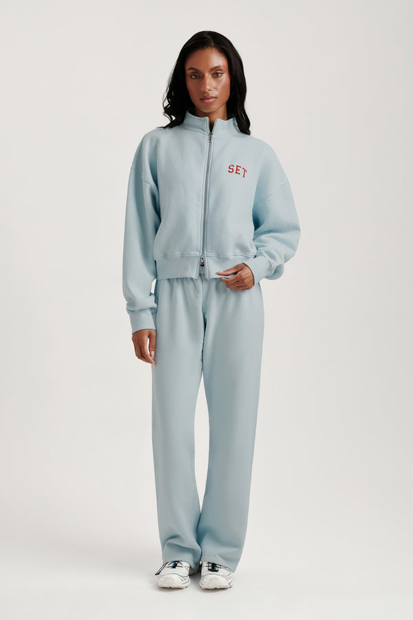 Person wearing a light blue tracksuit with 'SEY' branding on a white background