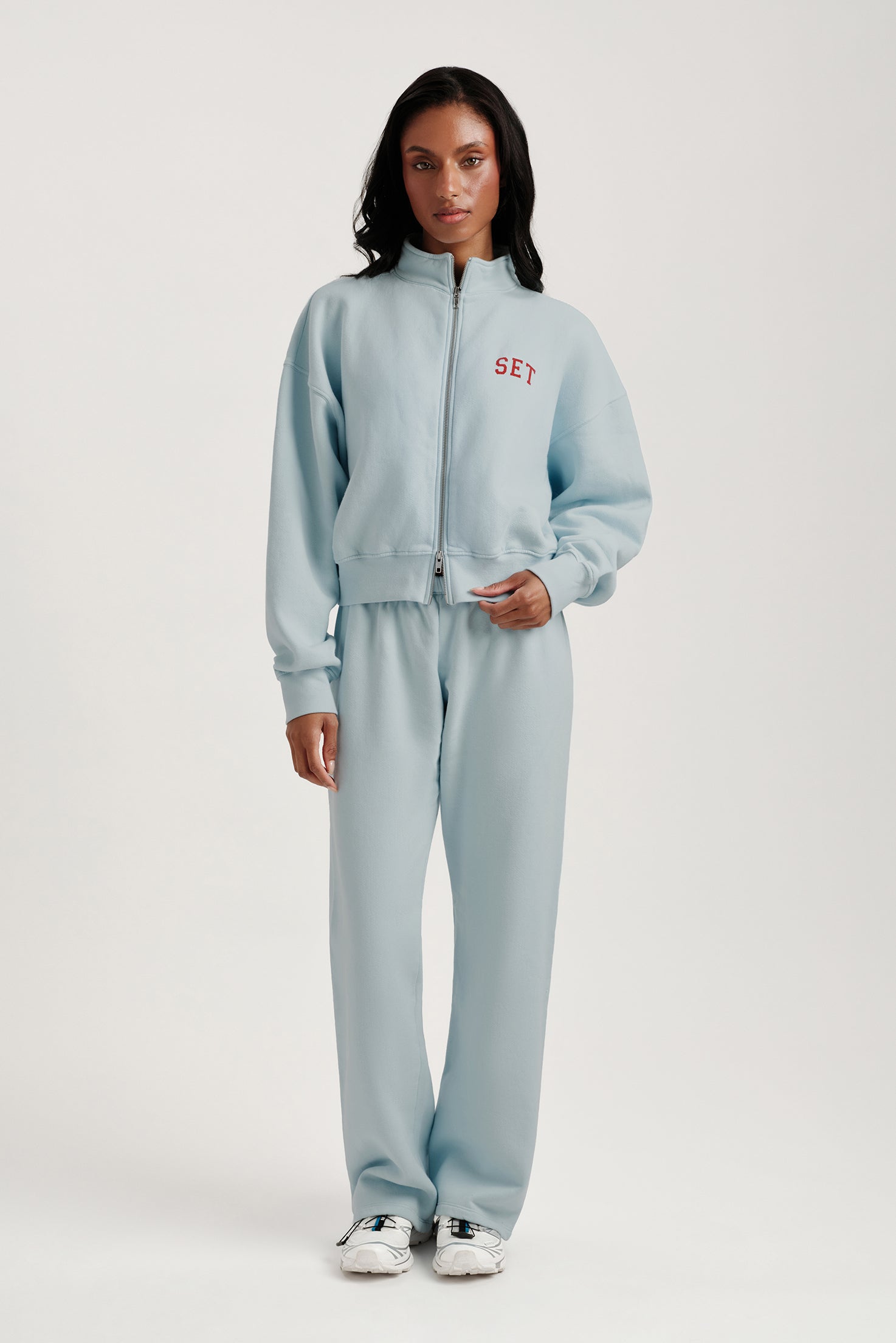 Person wearing a light blue tracksuit with 'SET' branding on a white background