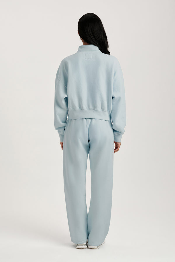 Person wearing a light blue tracksuit on a white background